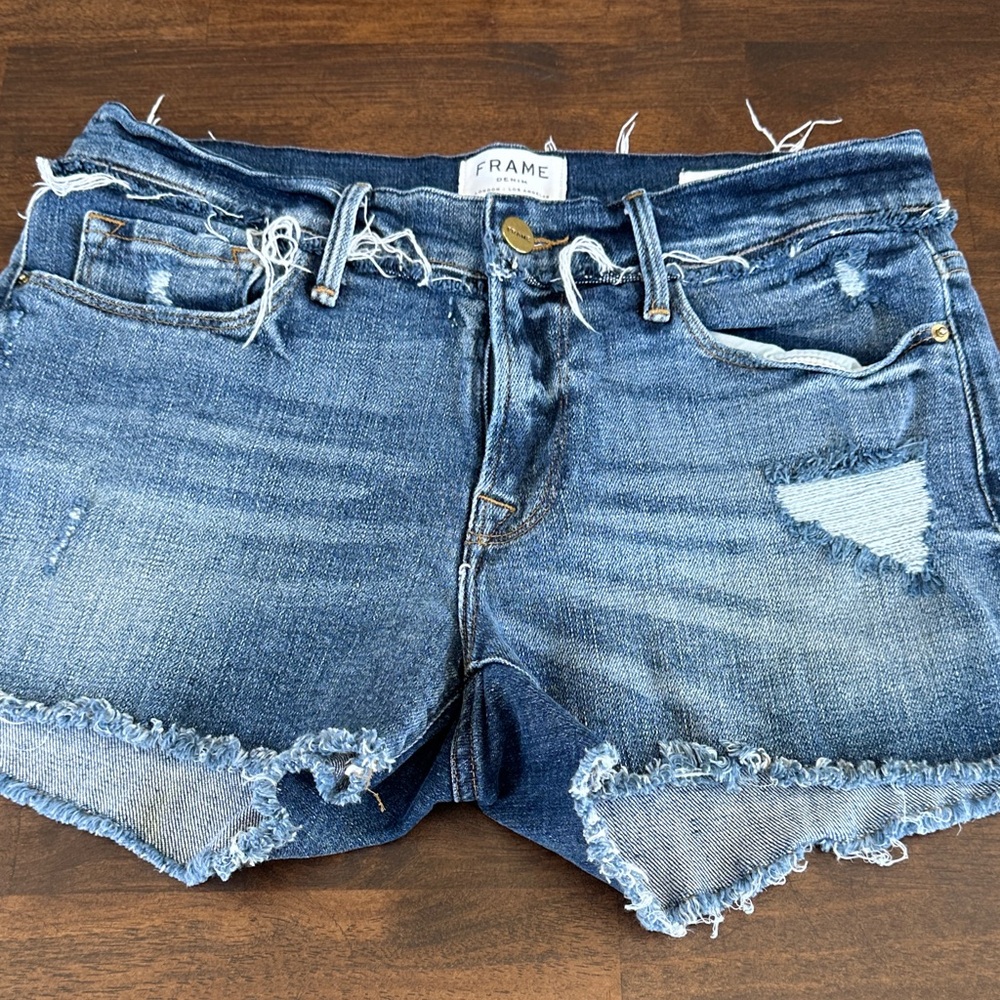 Frame Le Cutoff denim shorts feature distressing and a medium wash.
